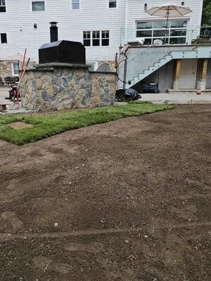 Graded residential lot with compacted soil, stone retaining wall, and prepared foundation area
