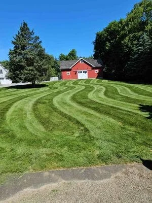 Striped lawn with alternating mow patterns in front of red residential home