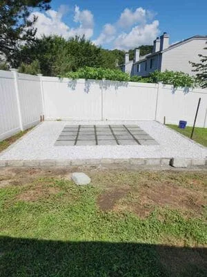 Permeable paver patio with geometric grid pattern and white vinyl fencing