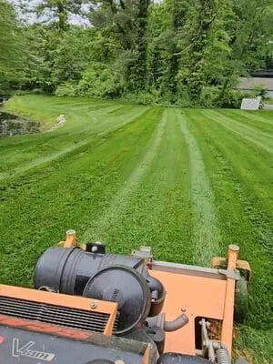Striped lawn mowing pattern with professional equipment on residential property